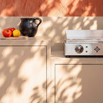 Cocina de exterior Pilotis blanco crema con plancha Vivaplancha y encimera de cerámica blanca.
::visuel:creme