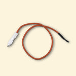 Câble piezo pour plancha gaz Vivaplancha, cordon orange avec allumeur céramique blanc, présenté sur fond beige.