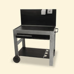 Chariot de plancha en bois et métal avec crédence noire, étagère inférieure, support à bouteilles, poignée latérale et deux roues arrière, présenté de face sur fond uni clair.