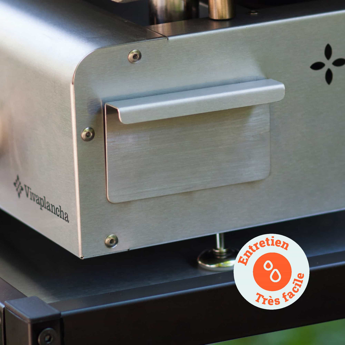 Enfoque en el recogedor de grasa de acero inoxidable de una plancha Vivaplancha, con una etiqueta “Mantenimiento muy fácil” que indica la sencillez de limpieza.