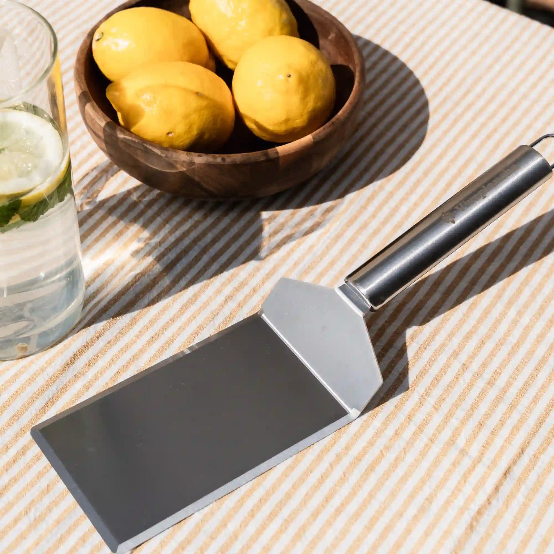 Spatule XL Vivaplancha posée sur une table près d'un bol de citrons