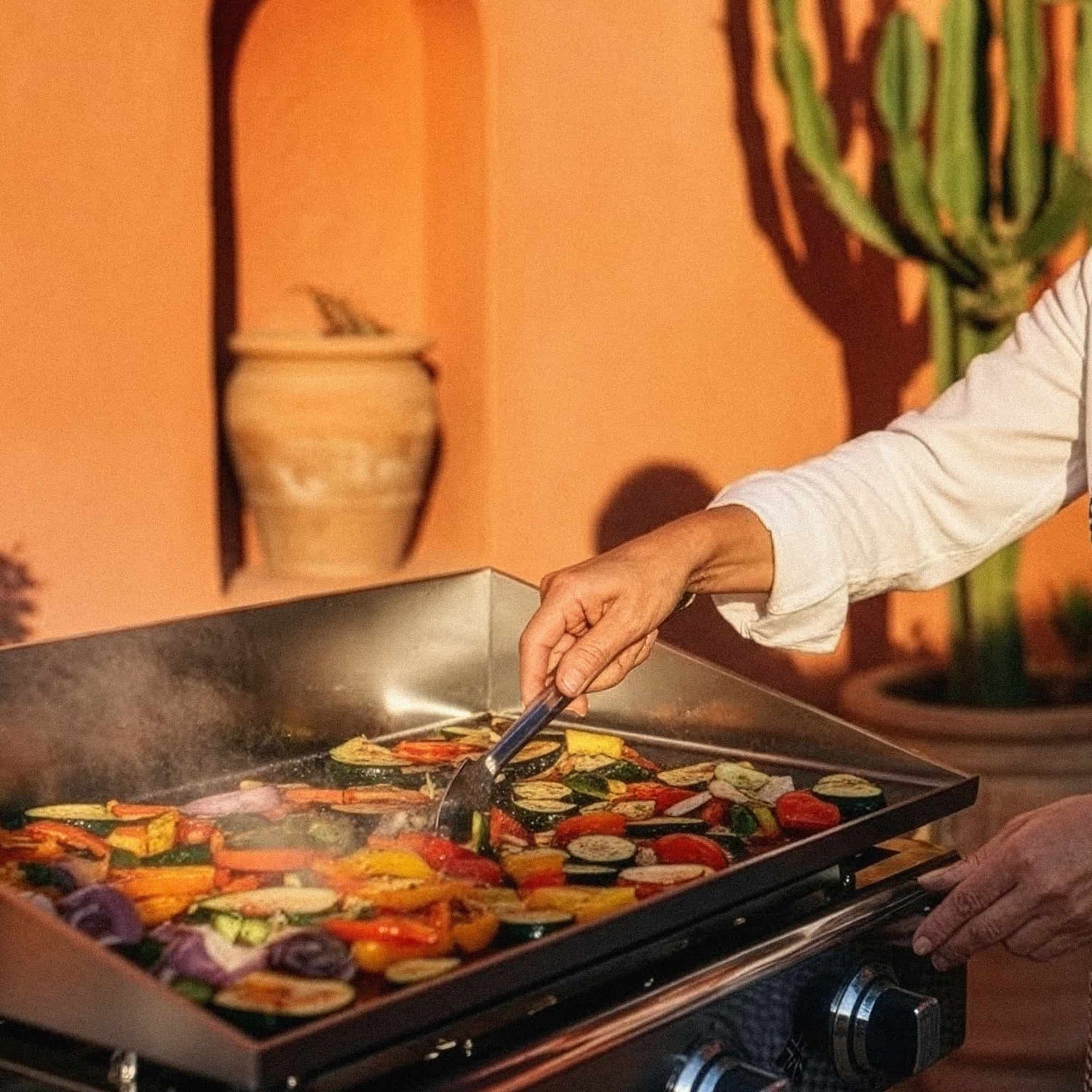 Chef cocinando verduras y carnes en una plancha de acero inoxidable Vivaplancha, control total de la cocción a alta temperatura